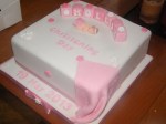 12 inch pink and white christening cake with letter blocks, a baby and a blanket