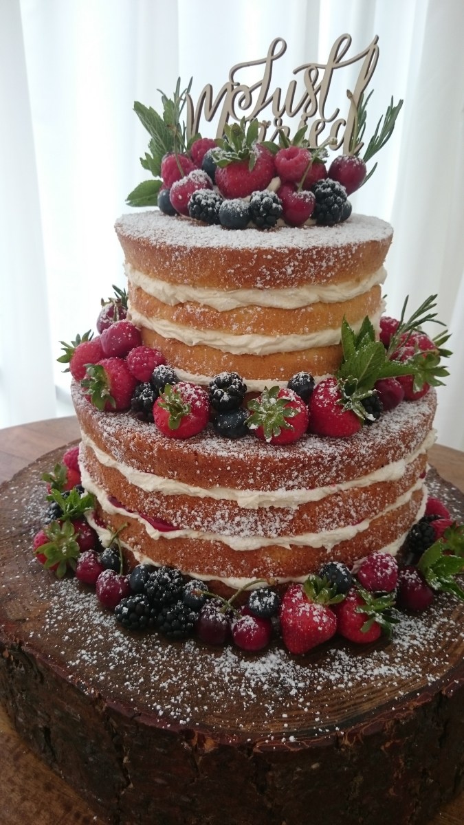 Rustic naked wedding cake with fresh fruit and herbs